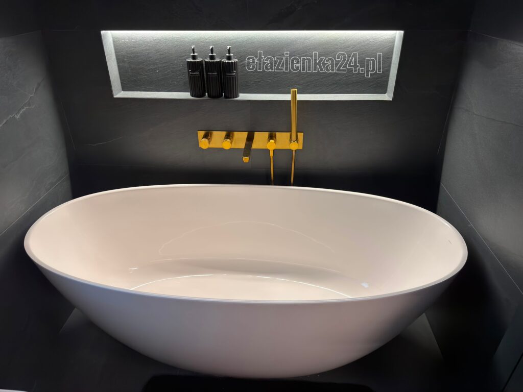 Owalna wanna wolnostojąca Marmorin Wika 160x70 w aranżacji ciemnego SPA ze złotą baterią podtynkową.