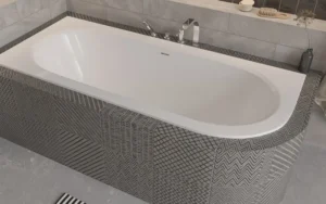 Besco Avita Slim Plus Wanna asymetryczna Besco Avita Slim Plus lewa z przelewem szczelinowym w obudowie z mozaiki i łazience z drewnianą podłogą.