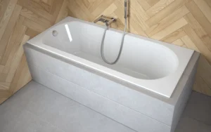 Wanna prostokątna Besco Shea Slim w zabudowie na tle płytek w jodełkę