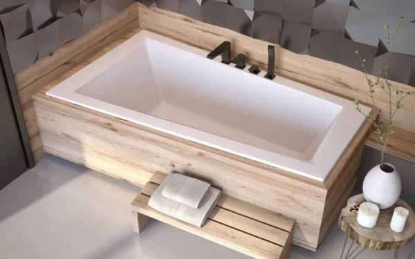 Wanna asymetryczna Besco Intima Slim do zabudowy w aranżacji z płytkami drewnopodobnymi i czarną baterią.
