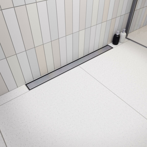 Elegancki odpływ przyścienny Vogi Premium SLX z gładkim rusztem ze szczotkowanej stali inox w jasnej aranżacji łazienki.
