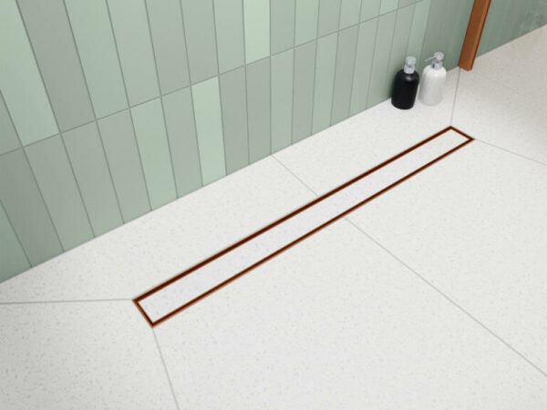 Odpływ liniowy Vogi Premium SLX Duo zamontowany pod prysznicem z wklejoną płytką ceramiczną i widoczną miedzianą ramką.
