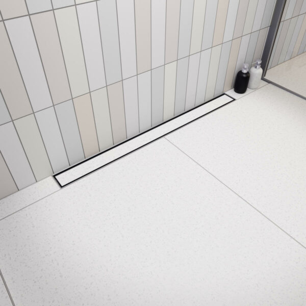 Nowoczesna kabina prysznicowa walk-in z odpływem przyściennym Vogi Premium SLX Duo zabudowanym jasnymi płytkami ceramicznymi.
