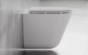Biała podwieszana miska WC Besco Laax Ergo zamontowana na szarej betonowej ścianie w łazience, widok z boku.