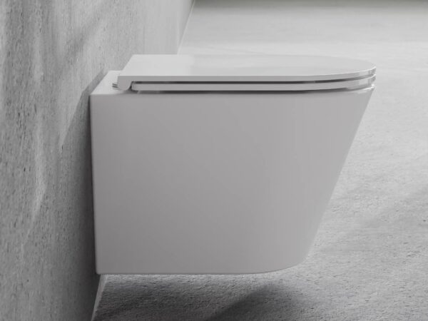 Miska WC Besco Laax White Biała podwieszana miska WC Besco Laax zamontowana na szarej betonowej ścianie nowoczesnej łazienki.