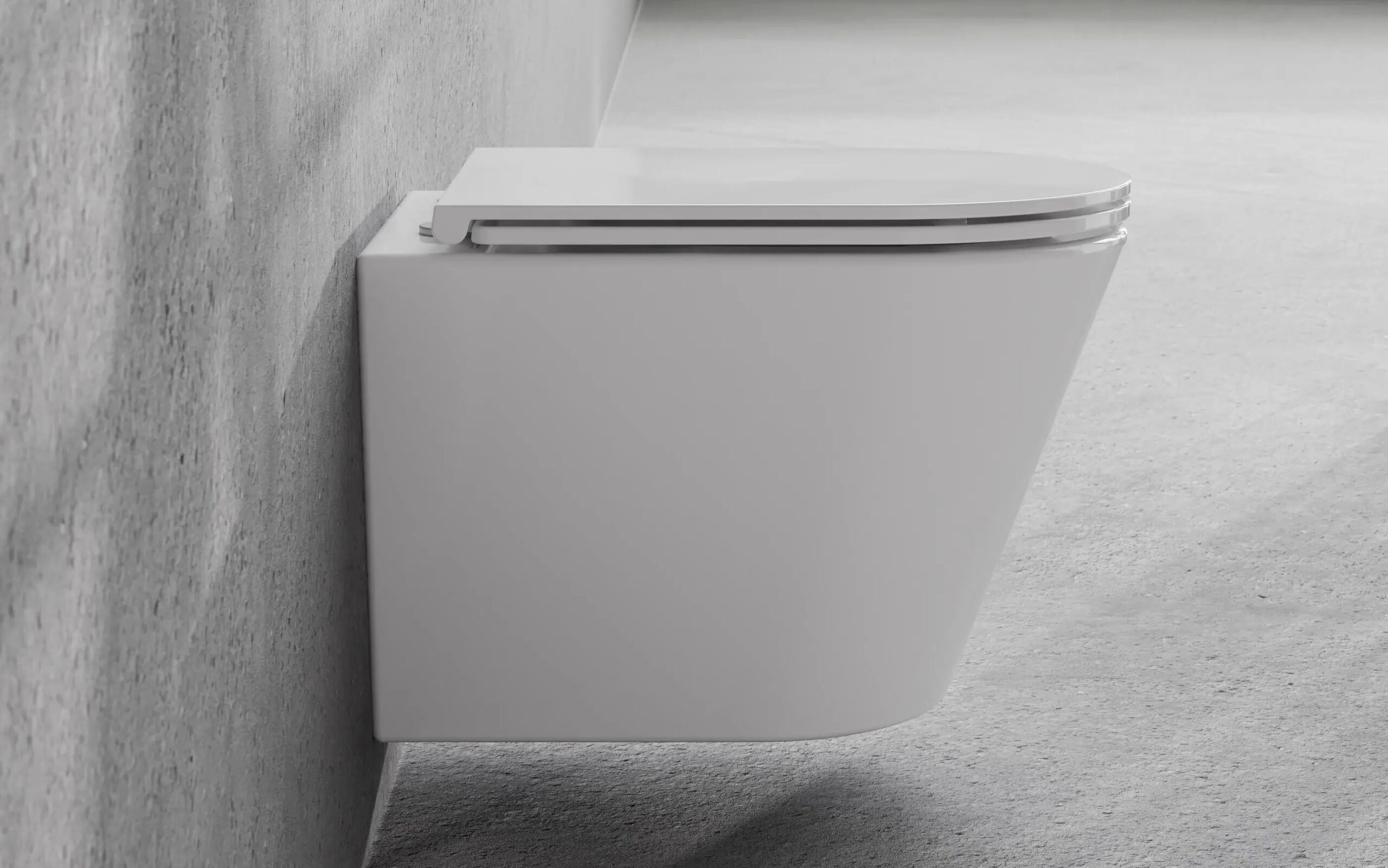 Miska WC Besco Laax White Biała podwieszana miska WC Besco Laax zamontowana na szarej betonowej ścianie nowoczesnej łazienki.